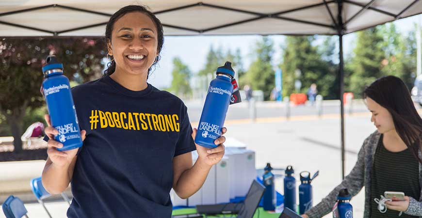 UC Staff member Breeana Sylvas poses outdoors with two reusable water bottles.