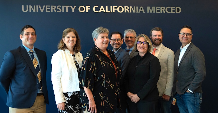 UC Merced and Almond Board officials are pictured underneath letters that spell out