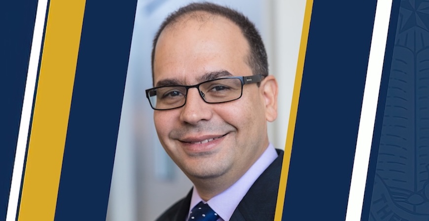 Photo is a mugshot of Professor Josué Medellín-Azuara depicted on a blue and gold background. 