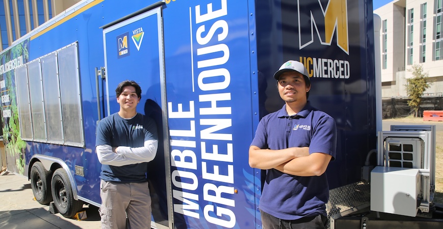 Specialists Isaac Leyva and Ethan Vu are pictured standing outside the blue trailer with white lettering reading